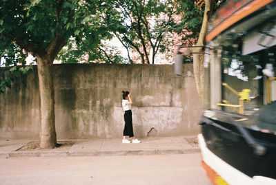 Side view of woman walking on sidewalk in city