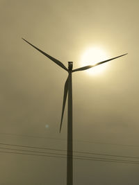 Low angle view of wind turbine against sky during sunset