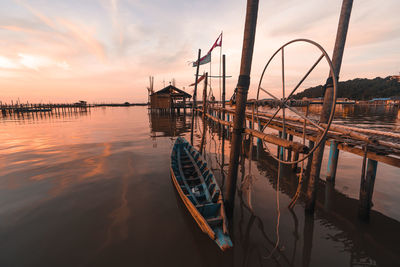 Sailboat moored at harbor against sky during sunset