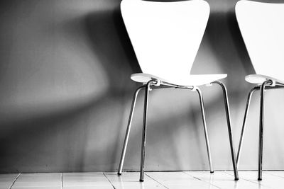 Close-up of empty seats on table against wall