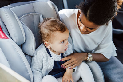 Rear view of mother and daughter sitting in car