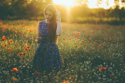 Young woman standing amidst poppy flowers