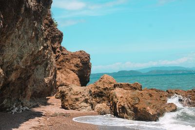 Rock formation on beach against sky