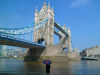 Rear view of woman standing by tower bridge against sky