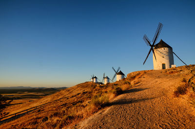 Traditional windmill on landscape against clear blue sky