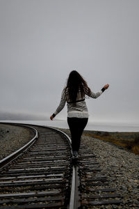 Rear view of woman standing on railroad track