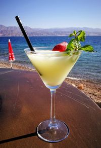 Wineglass on table at beach against sky