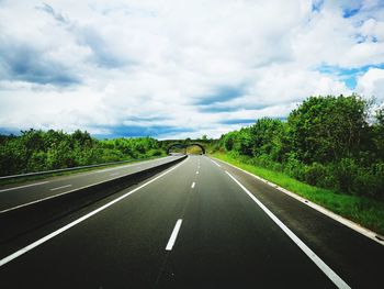 Road by trees against sky