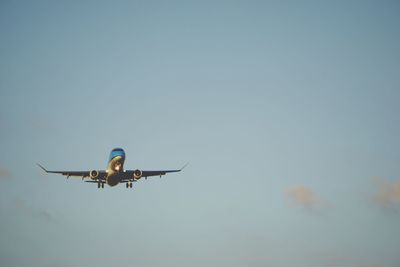 Low angle view of airplane flying against clear blue sky