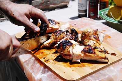 Close-up of hand cutting meat on board