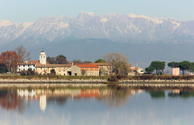 Houses by lake and mountains against sky