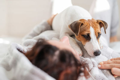 Woman lying down with dog on bed