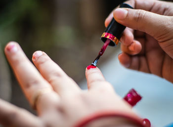 Young girl doing nail polish on nails at day in details