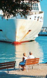 People sitting on seat at shore