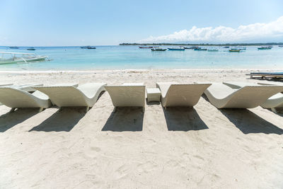 Lounge chairs at beach against sky