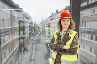 Portrait of smiling woman standing against buildings