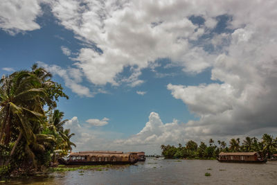 Boathouses in backwaters against cloudy sky