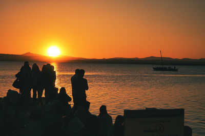 Silhouette people at beach against sky during sunset