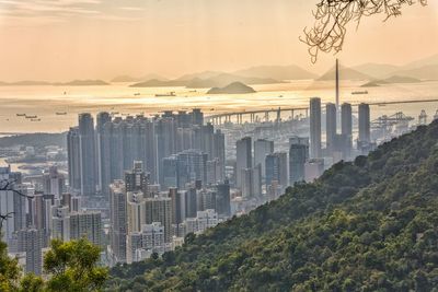 Cityscape by sea against sky during sunset