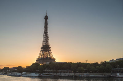 Communications tower in city against sky during sunset