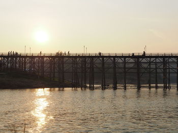 Bridge over river against sky during sunset