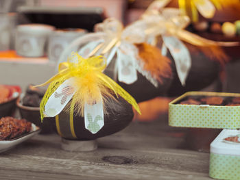 Chocolate eggs with ribbons and yellow feathers lie on a wooden background