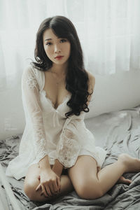 Portrait of young woman sitting on bed at home