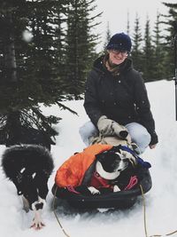 Young woman and dogs sitting in snow