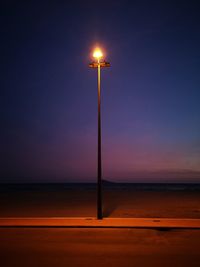 Street light by sea against sky at night
