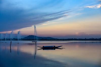 Silhouette boat in lake against sky during sunset