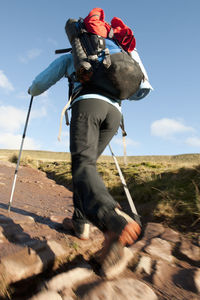 Low section of person riding horse on landscape against sky