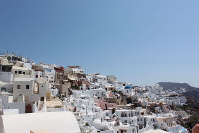 Buildings in city against clear blue sky