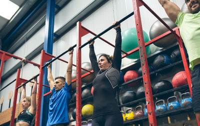 Low angle view of athletes hanging on exercise equipment in gym