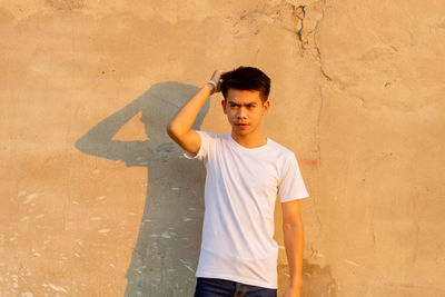 Full length of young man standing against wall