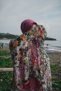 Rear view of women standing on shore against sky