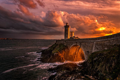 Lighthouse and bridge at sea during sunset