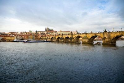 Bridge over river against cloudy sky