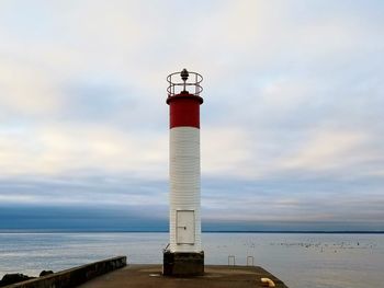 Lighthouse by sea against sky