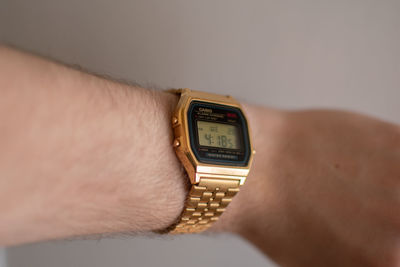 Close-up of human hand against clock