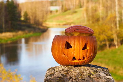 Halloween carved pumpkin with blurred landscape on the background.