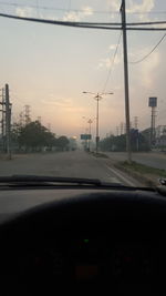 Close-up of road by city against sky during sunset