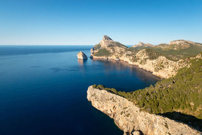 Scenic view of sea and mountains against clear blue sky