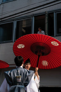 People with red umbrella standing outside building
