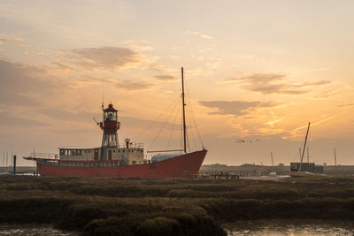 Sailboats moored on sea against sky during sunset