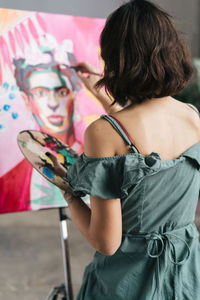 Rear view of woman painting on canvas at art studio