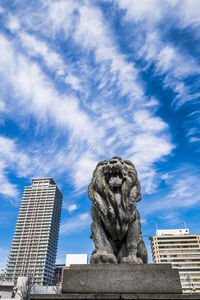 Low angle view of statue against buildings in city against sky