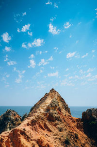 Rock formations by sea against blue sky