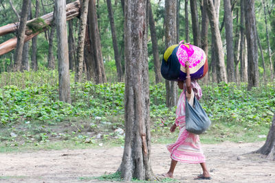 Full length of woman standing by tree in forest