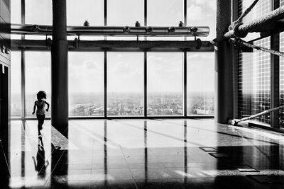 Woman standing by window against sky