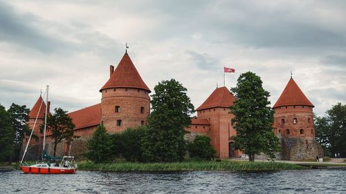 View of castle by the lake against cloudy sky